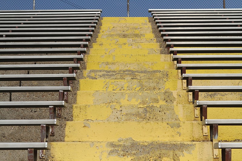 Rusted bleachers and chipped stairs cast shadows in the stands of the Howard High School stadium.