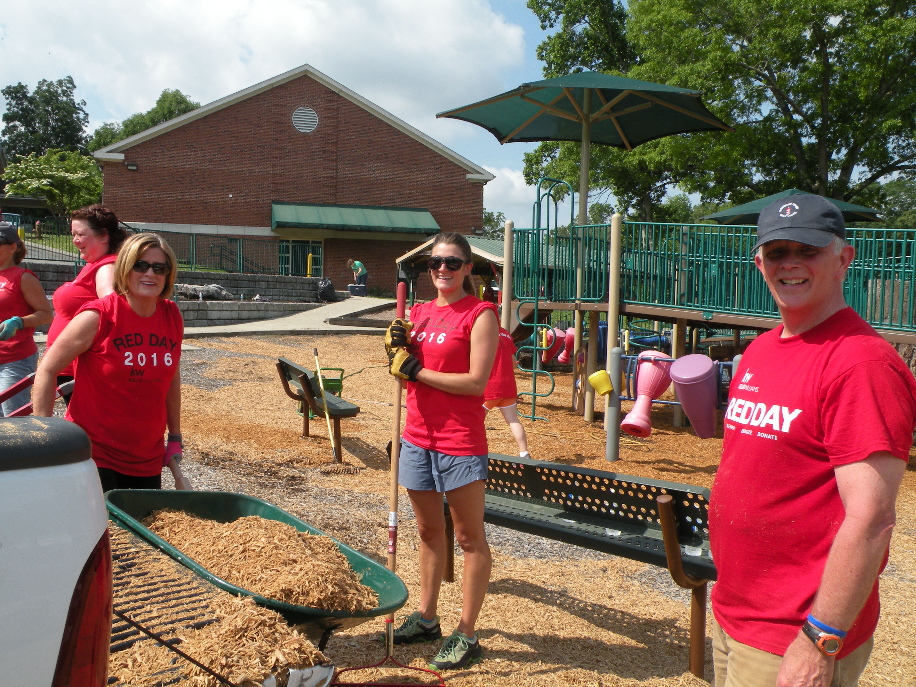 Susan Grimsley, Samantha Hefner and Mike Lane, from left, spread new mulch onto the playground.