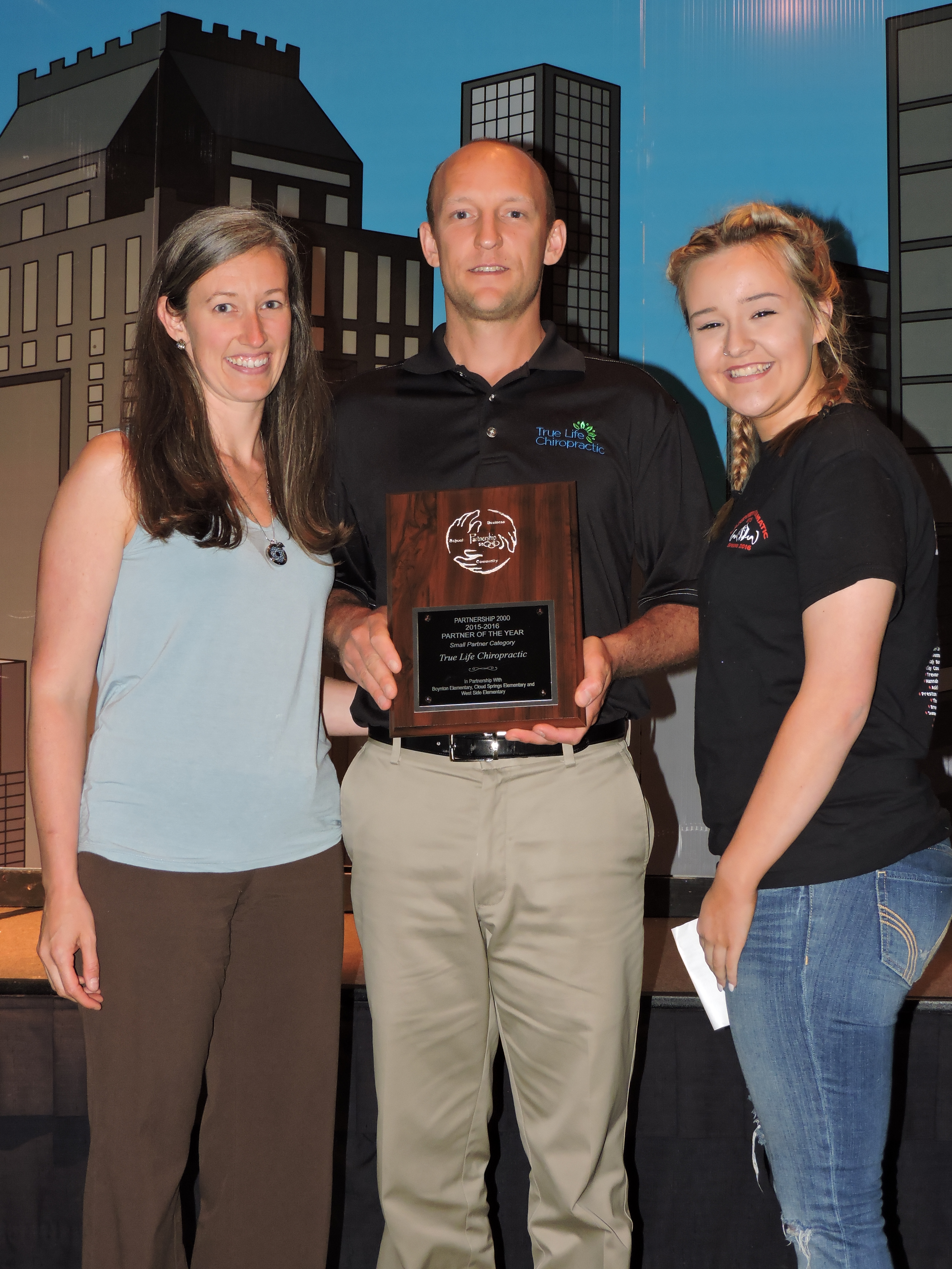From left, True Life Chiropractic's Samantha and Dr. Jamie accept the Small Partner of the Year award from Lakeview-Fort Oglethorpe High School student Olivia Richardson. The business collects canned food donations and delivers baskets to families of students at Thanksgiving and adopt students from school Angel Trees at Christmas. They also purchase classroom donations and help sponsor student field trips.