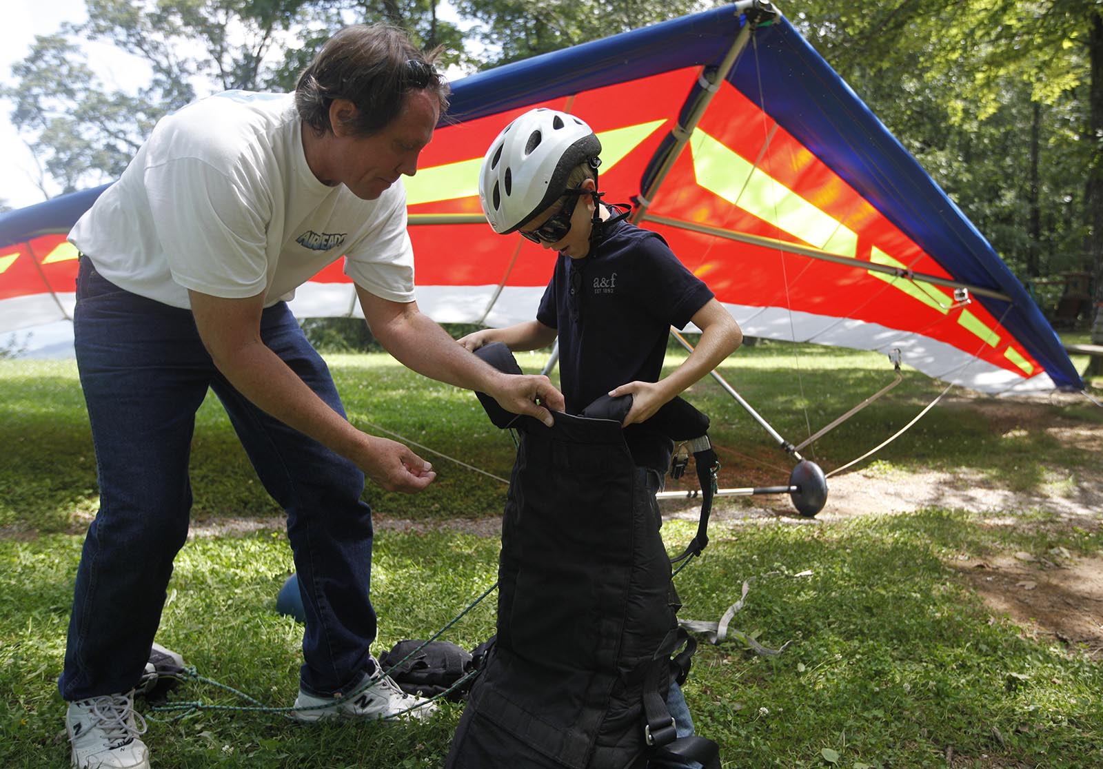Staff Photo by Doug Strickland/Chattanooga Times Free Press - July 25, 2013. Clark Harlow, who runs Thrill-A-Minute Sports, a tandem hang-gliding service, left, puts a harness onto passenger Luke Walker, 9, at the Tennessee Tree Toppers association's Henson's Gap launching area Thursday in Dunlap, Tenn.