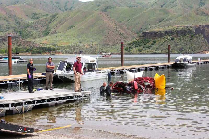 
              In this photo provided by the Ada County Sheriff's Office, Ada County Sheriff's Deputies and divers with the Boise Fire Department stand by the wreckage of an SUV driven by a 40-year-old Boise woman that plunged off a cliff into the Lucky Peak Reservoir Thursday, June 2, 2016, in Boise, Idaho. Divers with the Boise Fire Department recovered the bodies of two girls, ages 12 and 6, and the body of a 10-year-old boy from the vehicle, which was about 40 feet below the surface Thursday morning, according to the Ada County Sheriff's Office. A witness saw the SUV accelerate from the side of the road to go over the cliff, the sheriff's office said. (Patrick Orr/Ada County Sheriff's Office via AP)
            
