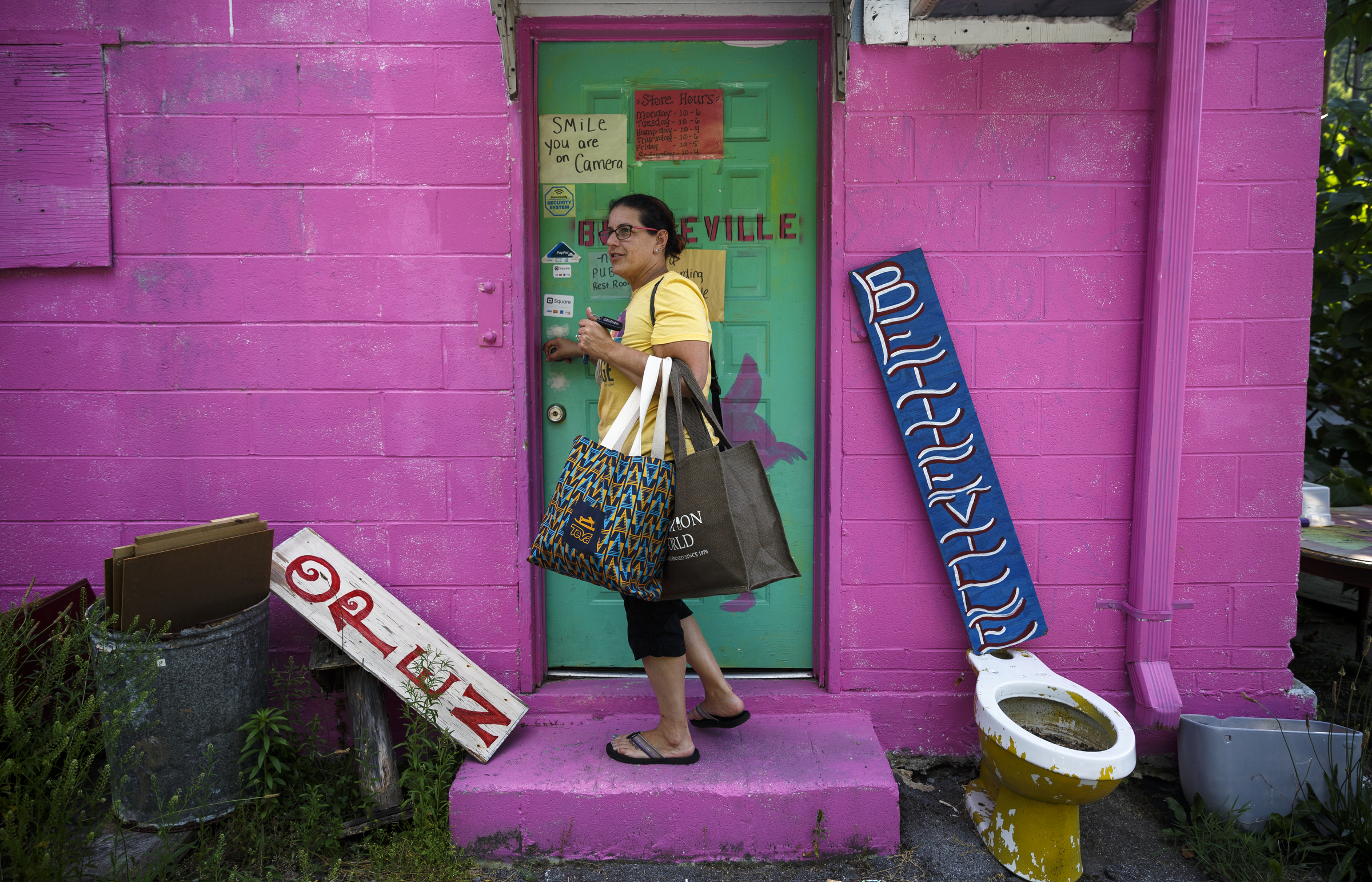 Jody Simon carries bags of clothes in the back door of Bettieville for a clothing swap party. Customers arrive with items to give away in the swap and maybe find something they can take home.