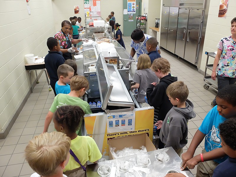 Battle Academy second grade students line up for lunch and receive help from nutrition workers Pearlie Mae Conner, left, and Josephine Marshall.