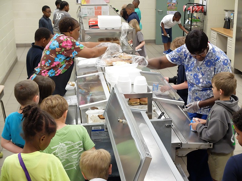 Battle Academy second grade students line up for lunch and receive help from nutrition workers Pearlie Mae Conner, left, and Josephine Marshall.