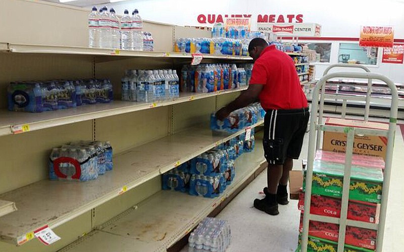 An employee stocks bottled water at a Foodvalu store in Courtland, Ala., Friday, June 3, 2016, after a local utility warned residents not to drink tap water because of chemical contamination. Store workers said they were struggling to keep water on the shelves after the alert. (AP Photo/Phillip Lucas)