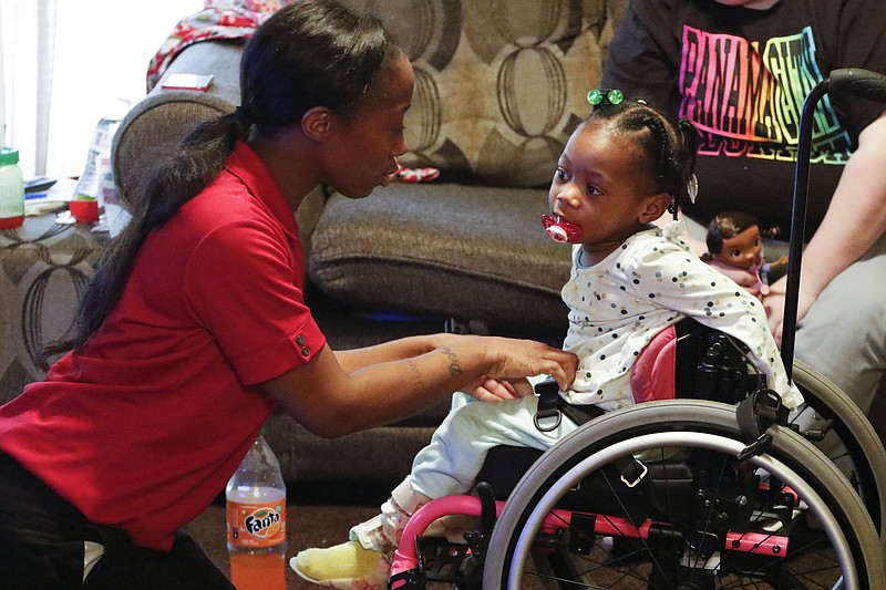Staff Photo by Dan Henry / The Chattanooga Times Free Press- 1/7/16. Two-year-old Zoey Duncan is buckled into her wheelchair by her mother Bianca Horton while at their apartment on Thursday, January 7, 2016. One year ago a gunman opened fire in a College Hill Courts apartment, killing a 20-year-old woman and wounding three others, including 1-year-old Zoey Duncan, who barely survived. Zoey was paralyzed from the waist down. A year later, she now gets around in a tiny toddler-sized pink wheelchair. 