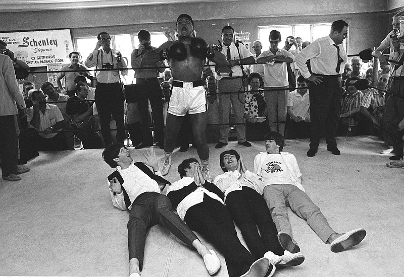 In this Feb. 18, 1964, file photo, boxer Muhammad Ali, or Cassius Clay at the time, beats his chest in triumph after toppling Britain's Beatles at his training camp in Miam i Beach, Fla. The Beatles, left to right: Paul McCartney; John Lennon; George Harrison and Ringo Starr, were on Holiday in the resort after their American tour. Ali, the magnificent heavyweight champion whose fast fists and irrepressible personality transcended sports and captivated the world, has died according to a statement released by his family Friday, June 3, 2016. He was 74. (AP Photo/File)