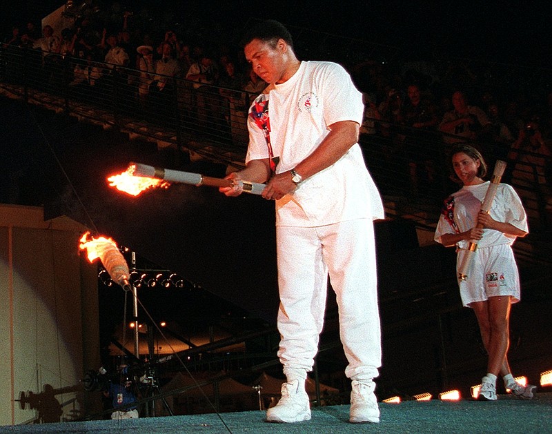 FILE - In this July 19, 1996, file photo, American swimmer Janet Evans looks on as Muhammad Ali lights the Olympic flame during the 1996 Summer Olympic Games opening ceremony in Atlanta. Ali, the magnificent heavyweight champion whose fast fists and irrepressible personality transcended sports and captivated the world, has died according to a statement released by his family Friday, June 3, 2016. He was 74.   (AP Photo/Michael Probst, File)