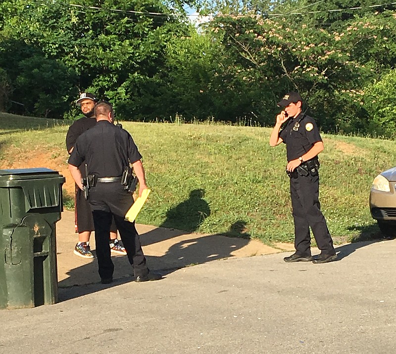 Officers talk with a man near the scene where a person was reportedly shot Monday afternoon in the Brainerd area of Chattanooga.