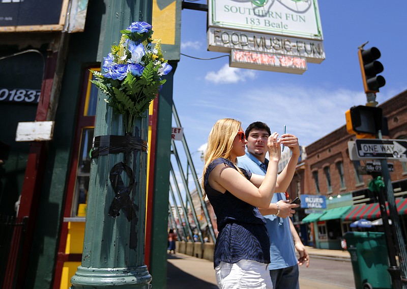 Tourists Jessica Wojciak, left, and Florian Alcade, from Chicago, take photos of Beale Street in Memphis, Tenn., on Sunday, June 5, 2016, next to one of two memorials at the intersection of B.B. King and Beale near the scene where Memphis Police Department Officer Verdell Smith was struck by a fleeing vehicle and killed. Justine Welch, 21, has been charged with multiple counts including murder and three counts of attempted murder in the crime spree that spread from the Pinch District to south of Beale.