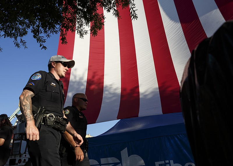 Chattanooga police Officers Steven Meador, left, and Jeremy Wilson walk past a large American flag as they monitor the crowd on the 1st day of the Riverbend Festival at Ross's Landing on Friday, June 10, 2016, in Chattanooga, Tenn. The festival is celebrating its 35th year, and Thomas Rhett was Friday night's headlining act.