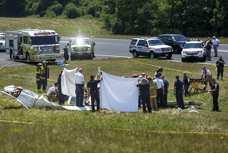 Emergency responders hold up white sheets as they remove the remains of 2 victims from the scene of a plane crash next to the runway of the Collegedale Municipal Airport on Saturday, June 11, 2016, in Collegedale, Tenn. There were 2 fatalities, and 2 victims were airlifted to Erlanger Hospital for treatment.