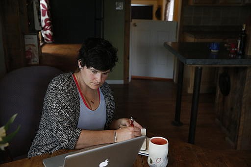 In this April 14, 2016 photo, activist and Soft Landing founder Mary Poole works at home in Missoula, Mont. Haunted by the 2015 photo of a Syrian refugee boy washed ashore in Turkey, she and members of her book group asked: Why not bring a small number of Syrian families to Missoula? "It wasn't even a grain of sand in my brain that people wouldn't want to help starving, drowning families. I didn't do this to be controversial. I didn't do this to stir the pot," she says. (AP Photo/Brennan Linsley)