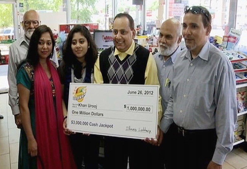 
              FILE - This June 2012 file photo provided by WMAQ-TV in Chicago, shows Urooj Khan, center, holding a ceremonial check in Chicago for $1 million as winner of an Illinois instant lottery game. At left, is Khan's wife, Shabana Ansari. Khan died suddenly on July 20, 2012, just days before he was to collect his winnings. With his departure from office this week, Stephen Cina, the former Cook County medical examiner leaves behind a beguiling mystery that he set in motion with a sensational declaration three years ago that Khan was poisoned with cyanide. (Courtesy of WMAQ-TV in Chicago via AP, File)
            