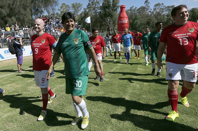
              FILE - In this March 31, 2016, file photo, Bolivia's President Evo Morales, center, FIFA President Gianni Infantino, left, and Conmebol President Alejandro Dominguez, right, enter the field before a friendly soccer match in Cochabamba, Bolivia. President Morales has been released from a hospital on Sunday, June 12, 2016, after knee surgery to correct a soccer injury.(AP Photo/Juan Karita, File)
            