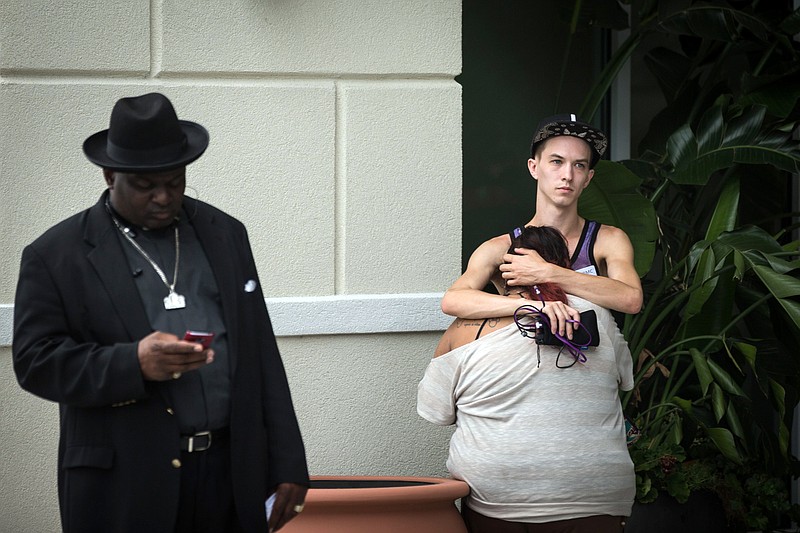 
              People grieve outside a Hampton Inn & Suites hotel, which turned into a hub for families and friends waiting to hear about loved ones because of its proximity to the Orlando Regional Medical Center, in the wake of a mass shooting that took place the prior night in Orlando, Fla., on Sunday, June 12, 2016.  (Loren Elliott/The Tampa Bay Times via AP)
            