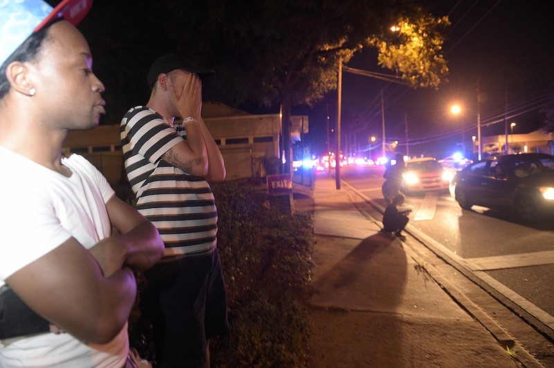 Jermaine Towns, left, and Brandon Shuford wait down the street from a multiple shooting at a nightclub in Orlando, Fla., Sunday, June 12, 2016. Towns said his brother was in the club at the time. A gunman opened fire at a nightclub in central Florida. (AP Photo/Phelan M. Ebenhack)