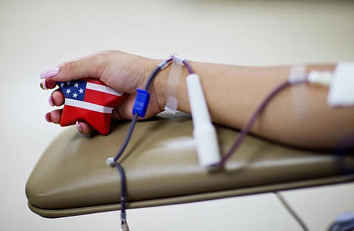Tatiana Osorio, of Orlando, squeezes an American-flagged themed stress ball while giving blood at the OneBlood blood center near the mass shooting at a nightclub Monday, June 13, 2016, in Orlando, Fla. Osorio lost three friends in the shooting. (AP Photo/David Goldman)
