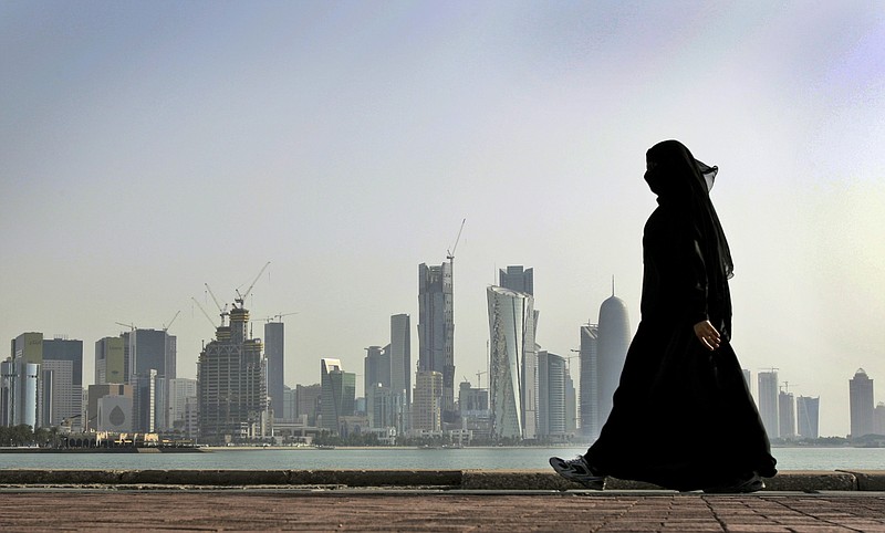 
              FILE- In this May 14, 2010 file photo, a Qatari woman walks in front of the city skyline in Doha, Qatar. A Dutch woman held in Qatar for nearly three months after telling police she had been raped was released Monday after receiving a 1-year suspended prison sentence, a Dutch diplomat said Monday. (AP Photo/Kamran Jebreili, File)
            