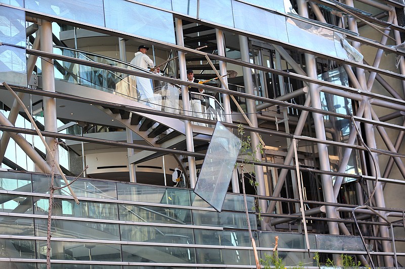 
              Police investigators remove broken windows from the damaged headquarters building of Blom Bank where a bomb exploded Sunday evening, in Beirut, Lebanon, Monday, June 13, 2016. Blom Bank has been criticized by some pro-Hezbollah politicians for taking a hard-line position after Lebanese banks began abiding by a U.S. law that sanctions doing business with the militant group. Authorities say dozens of bank accounts related to Hezbollah's organizations have been closed in recent weeks. (AP Photo/Hussein Malla)
            