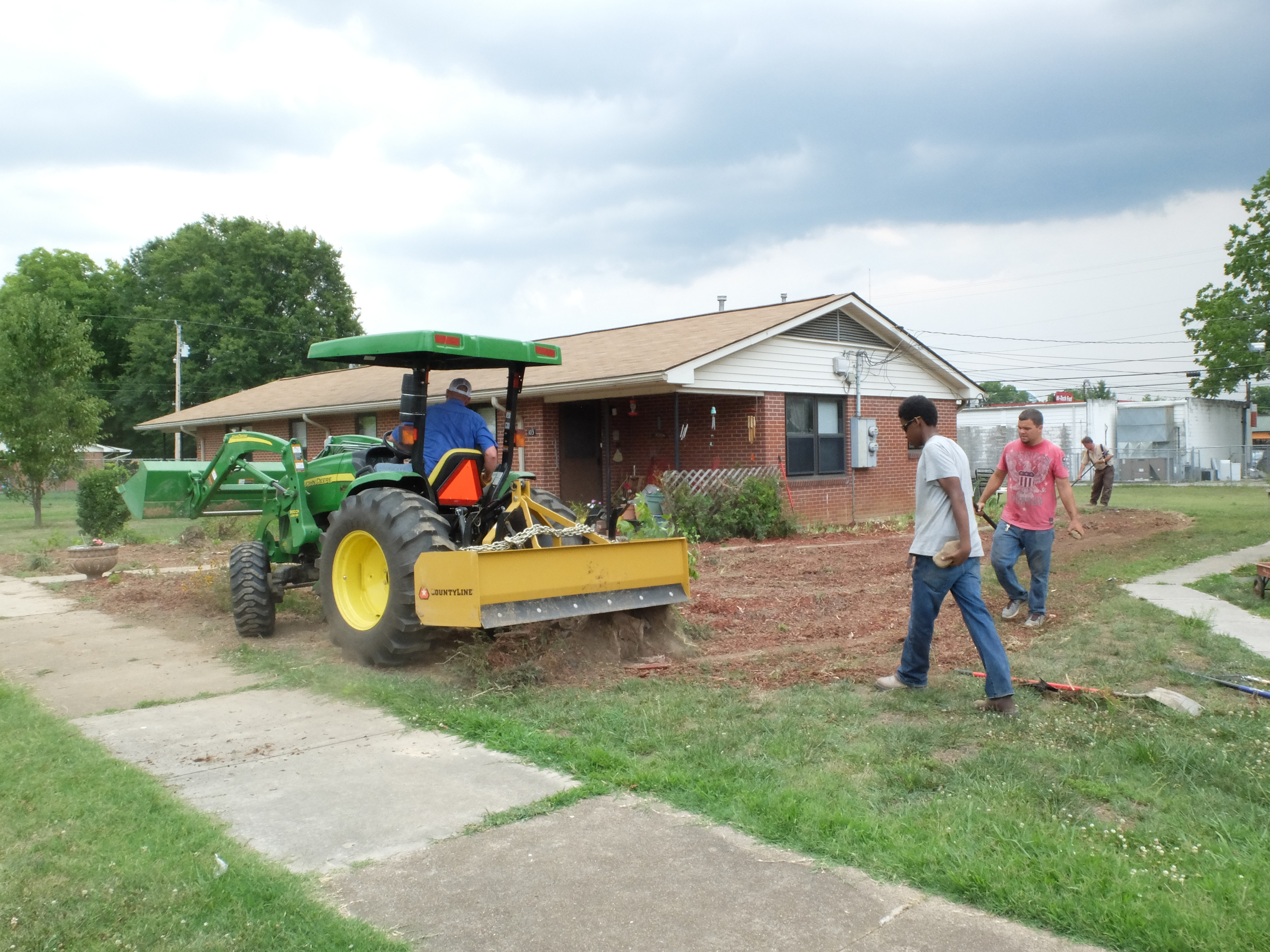 Driving a dirt grading tractor, Phillip Smith, maintenance manager for the South Pittsburg Housing Authority, works with his crew to restore the yard at 103 Elm Ave. where the resident had a flower garden that encompassed the entire property.