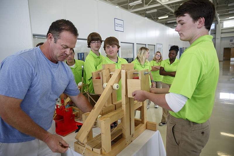 Teacher Chip Strickland, left, and Bryce Tank, right, demonstrate the operation of a trebuchet made by mechatronics students at the Volkswagen manufacturing plant on Thursday, June 16, 2016, in Chattanooga, Tenn. This fall, 27 Hamilton County high school juniors will enroll in Volkswagen's new Mechatronics Akademie where they will spend 2 years learning how to run and maintain industrial robots.