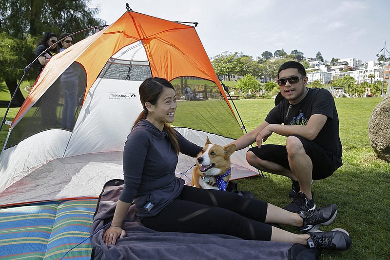 
              In this photo taken Saturday, May 28, 2016, Maria Santiago, left, of Daly City, Calif., sits with her dog, Bullit and husband, Joe Maniego, at Dolores Park in San Francisco. A proposal to let people reserve grassy plots of picnic lawn at a popular San Francisco park hit a collective nerve when it was unveiled last month: Within hours, thousands of people signed an online petition to kill the plan, a protest was scheduled and city leaders declared the grass wasn't for sale or rent. (AP Photo/Eric Risberg)
            