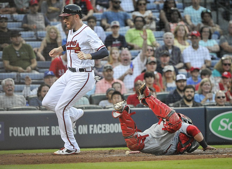 Atlanta Braves' Freddie Freeman scores on a Jace Peterson ground ball to third base as Cincinnati Reds catcher Ramon Cabrera dives to attempt a tag during the third inning of a baseball game, Wednesday, June 15, 2016, in Atlanta. (AP Photo/John Amis)
