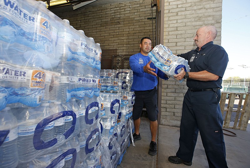 
              Glendale Fire Department firefighter Chris Greene, right, gets a case of water from service worker Edi Marroquin, left, from the dozens of cases of water at the Glendale Fire Department Resource Center as they prepare for the record-setting heat predicted for the weekend Thursday, June 16, 2016, in Glendale, Ariz. (AP Photo/Ross D. Franklin)
            