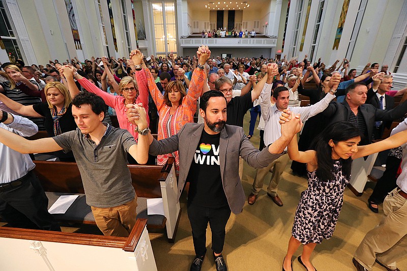 In this Tuesday, June 14, 2016 file photo, worshippers joins hands during an interfaith service at the First United Methodist Church of Orlando, Fla. A gunman killed dozens of people at a gay nightclub in Orlando on Sunday, making it the worst mass shooting in modern U.S. history. (Curtis Compton/Atlanta Journal-Constitution via AP)