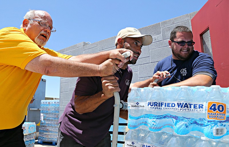 
              This Tuesday, June 14, 2016 photo Leo Block, left, Matari Phason, center, and Brian Juarez, right, push part of a shipment of 20,000 water bottles donated by Yellow Cab of Phoenix to Central Arizona Shelter Services, Arizona's largest homeless shelter, to help prepare for the summer heat in Phoenix, Ariz. (AP Photo/Ryan Van Velzer)
            
