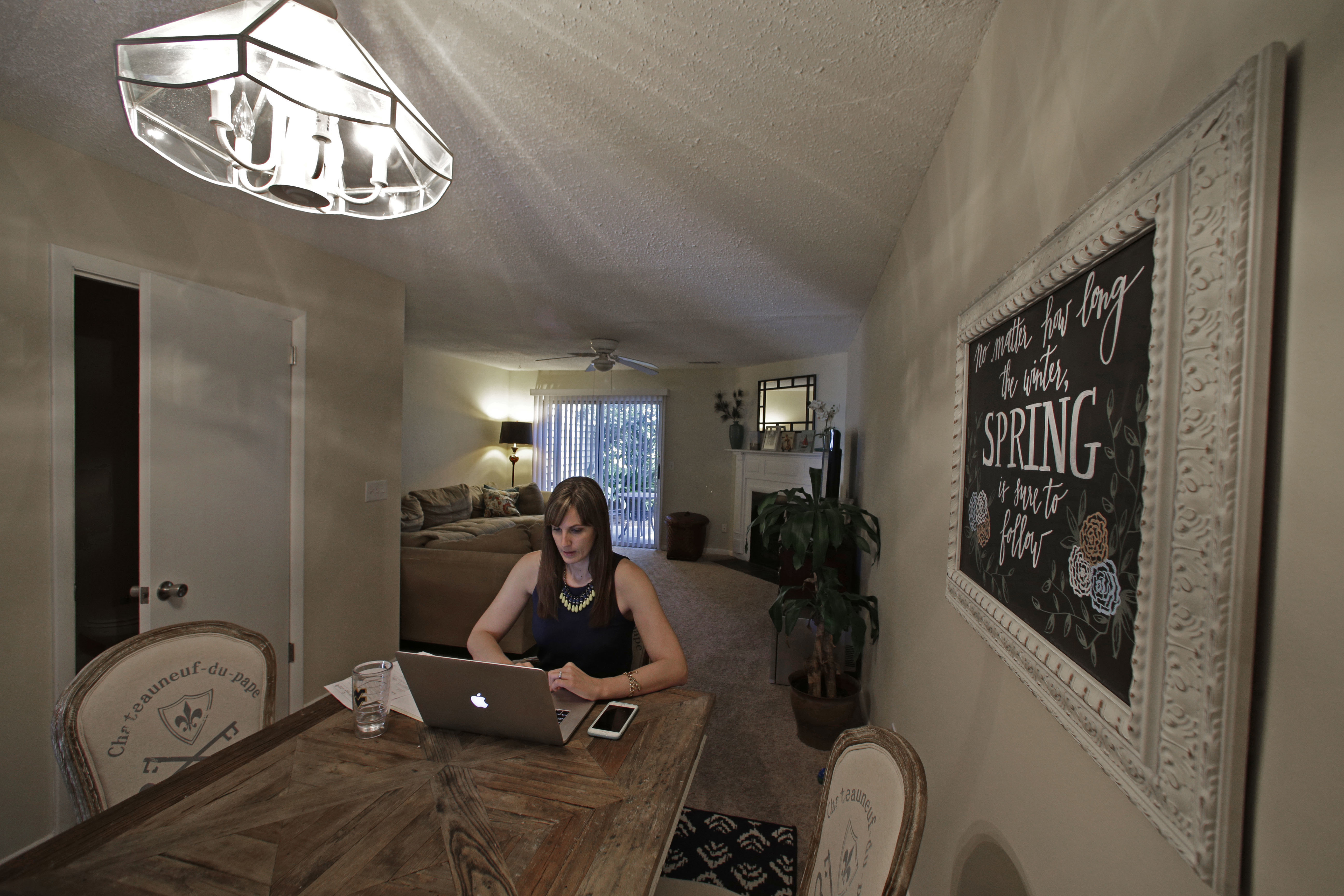 In this Tuesday, April 19, 2016, photo, Christi Fabie works at her dining table at the rental home she shares with her husband, Joe Fabie, in Charleston, S.C. The Fabies left Mount Pleasant, S.C., to rent somewhere cheaper. Both have law school debt and are saving to buy a home. (AP Photo/Chuck Burton)