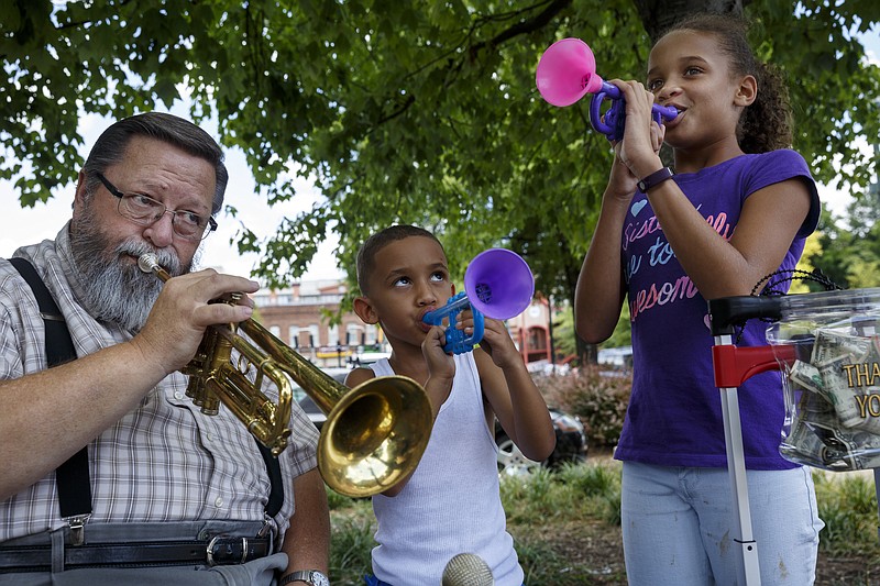 Randy Croy, left, plays trumpet along with Jaxon McCord, center, and Jazalyn McCord, who got their plastic trumpets from Croy.