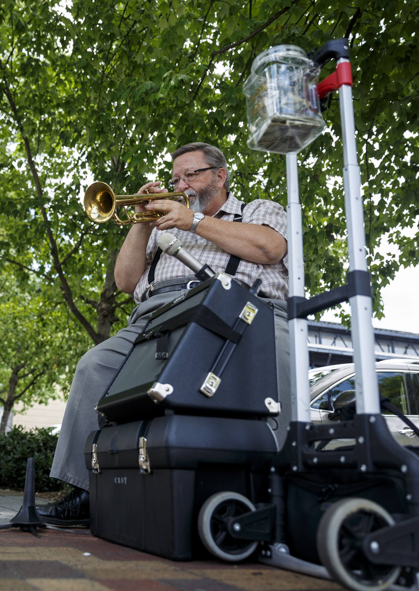 Randy Croy plays trumpet while busking — the art of street performance for tips — at the intersection of Broad Street and Aquarium Way.
