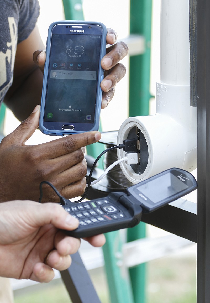 Staff Photo by Dan Henry / The Chattanooga Times Free Press- 6/22/16. Ajani Bakari, left, and Dr. Michael Pugh install a solar and capacitor based phone charger on Wednesday, June 22, 2016, at a pavilion previously designated for smokers on the Chattanooga State campus. 