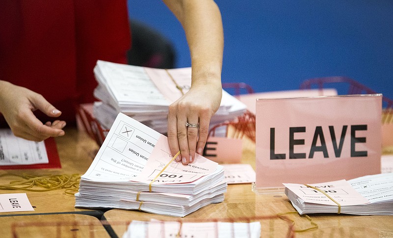 A teller counts ballot papers at the Titanic Exhibition Centre in Belfast, Northern Ireland, after polls closed in the EU referendum Thursday, June 23, 2016. Britain's referendum on whether to leave the European Union was too close to call early Friday, with increasingly mixed signals challenging earlier indications that "remain" had won a narrow victory. (Liam McBurney/PA via AP)