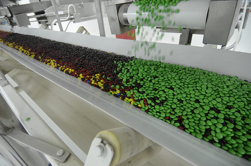 M&M's spill onto a conveyor belt at the M&M Mars candy plant on Peerless Road in Cleveland, Tenn.