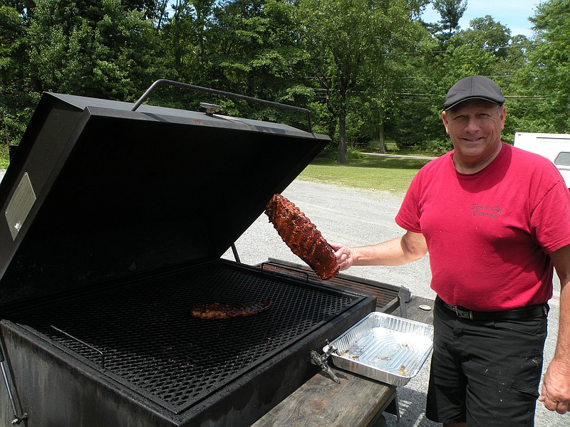 Scenic City Catering and BBQ 2 U co-owner Steve Brouse smokes ribs on his smoker outside the business in Ashley Plaza.