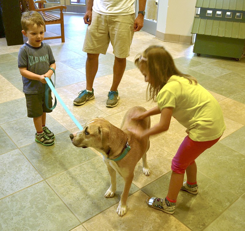 Charlie and Maggie Clemons play with their new dog Gracie Lou after adopting the animal at the McKamey Center.  The childrens's father, Blake, looks on in the background. 