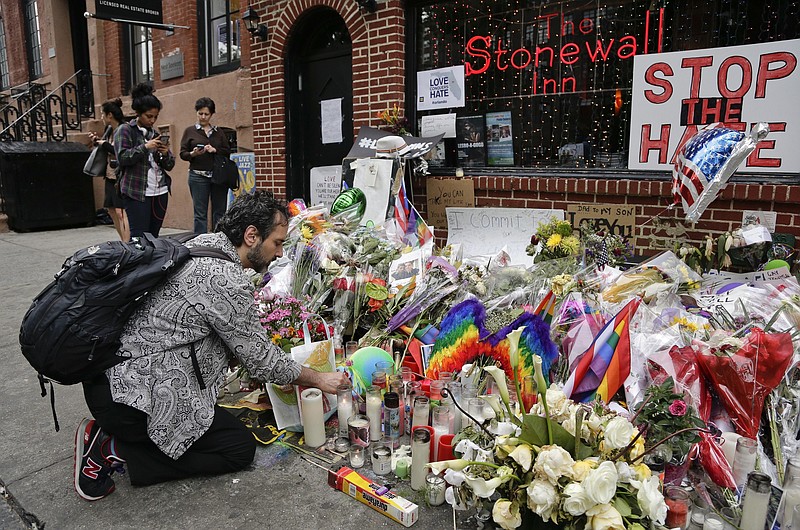 
              FILE - In this June 16, 2016 file photo, a man lights candles on a memorial outside the Stonewall Inn for victims of the Orlando Shooting, in New York. President Barack Obama is designating the Stonewall Inn in New York a national monument, the first to honor gay rights. AP (AP Photo/Julie Jacobson, File)
            