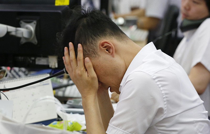 A currency trader rubs his eyes at the foreign exchange dealing room in Seoul, South Korea, Friday, June 24, 2016. Asian stock markets were volatile on Friday with Tokyo stocks and U.S. futures plunging as early vote results on whether Britain should stay in the European Union showed a tight race. (AP Photo/Lee Jin-man)