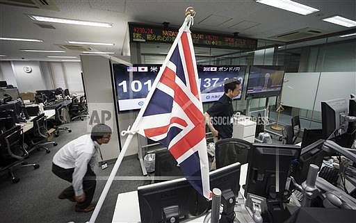 Money traders walk past a flag of the United Kingdom at a foreign exchange brokerage at a securities firm in Tokyo, Friday, June 24, 2016. Global financial markets fluctuated on Friday as votes are tallied in the referendum deciding if Britain is to leave the European Union. (AP Photo/Eugene Hoshiko)