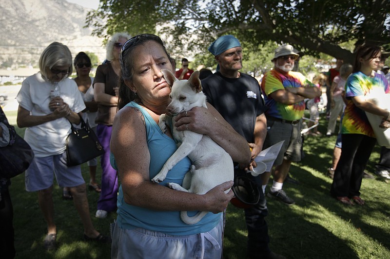 
              Evacuee Kimberly Tieche holds her 10-month old puppy while listening to the briefing on a wildfire at an evacuation center, Saturday, June 25, 2016, near Kernville, Calif. Tieche whose home was devastated by the wildfire said she only had five minutes to get out. (AP Photo/Jae C. Hong)
            