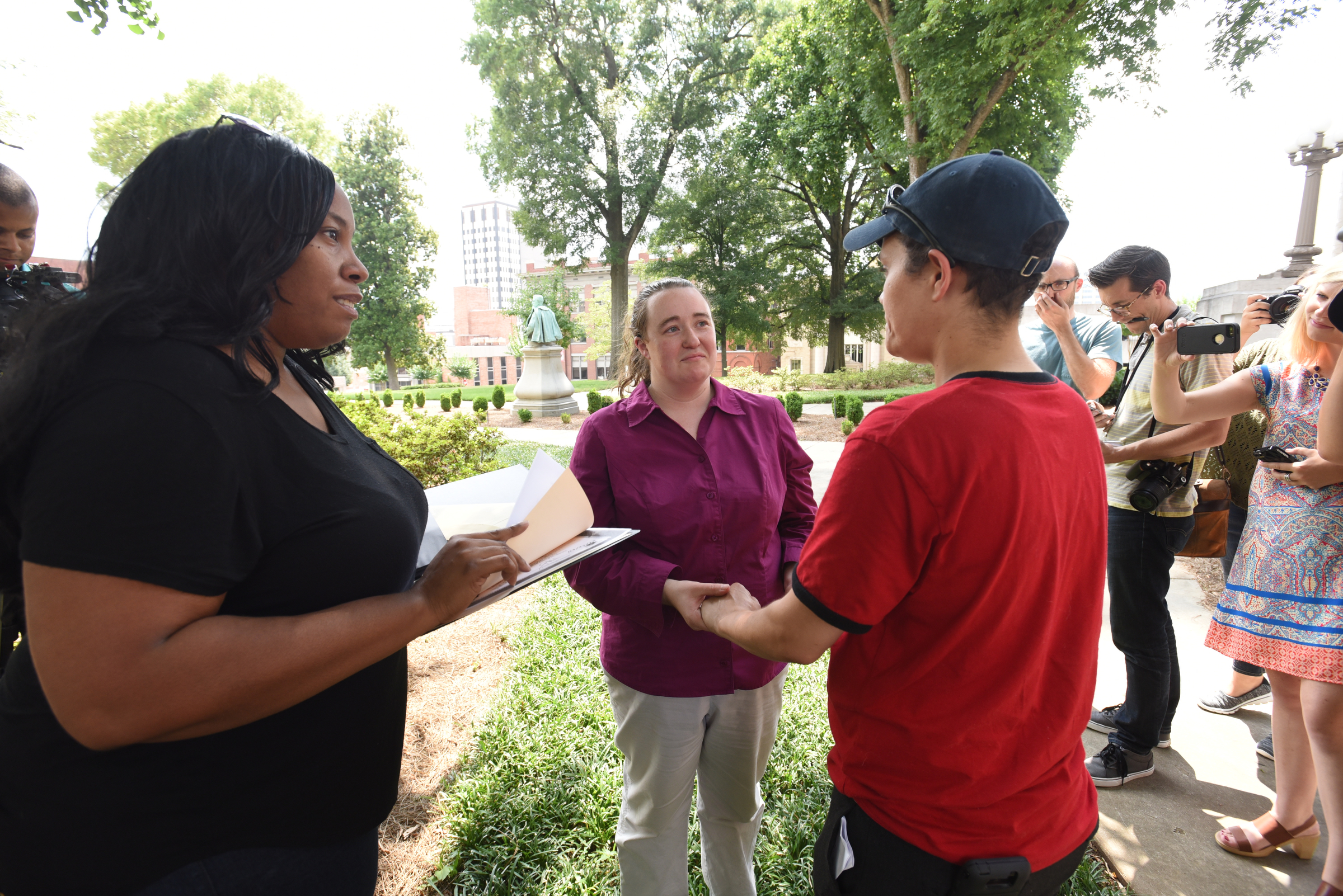 Celebrant Shaun Cox gets ready to perform the wedding ceremony as Phyllis Wood, center, and Rhiannan Pierce holds hands Friday, June 26, 2015 at the Hamilton County Courthouse.