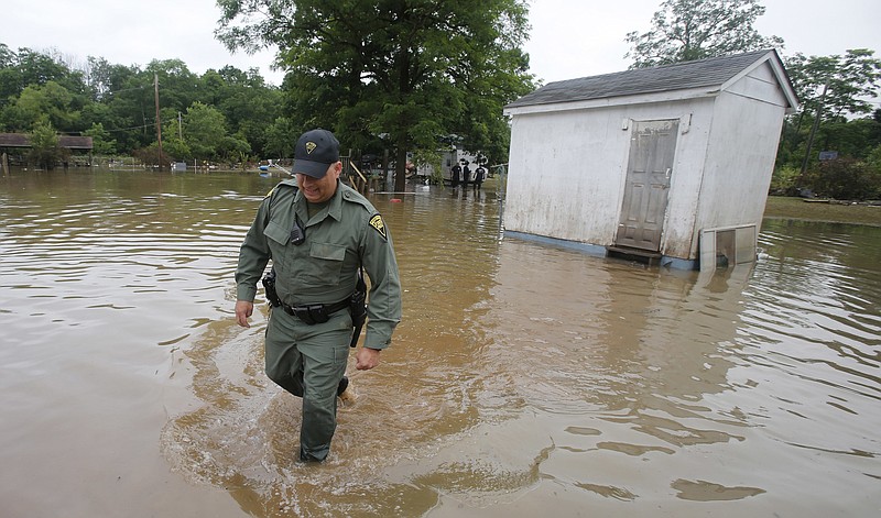 
              West Virginia State Trooper C.S. Hartman, walks from a shed that he checked out as he and other crews search homes in Rainelle, W. Va., Saturday, June 25, 2016. Heavy rains that pummeled West Virginia left multiple people dead, and authorities said Saturday that an unknown number of people in the hardest-hit county remained unaccounted for. (AP Photo/Steve Helber)
            