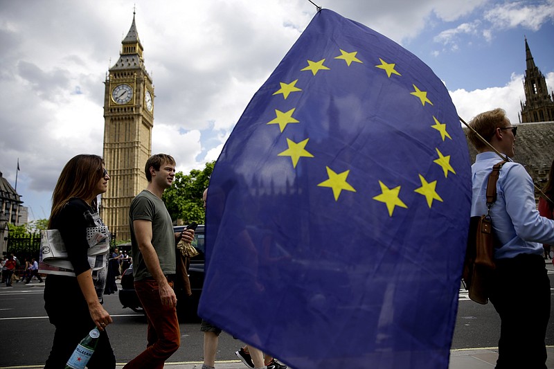 A remain supporter stops to talk to people as he walks around with his European flag across the street from the Houses of Parliament in London, Friday, June 24, 2016. Britain's Prime Minister David Cameron announced Friday that he will quit as Prime Minister following a defeat in the referendum which ended with a vote for Britain to leave the European Union. (AP Photo/Matt Dunham)
