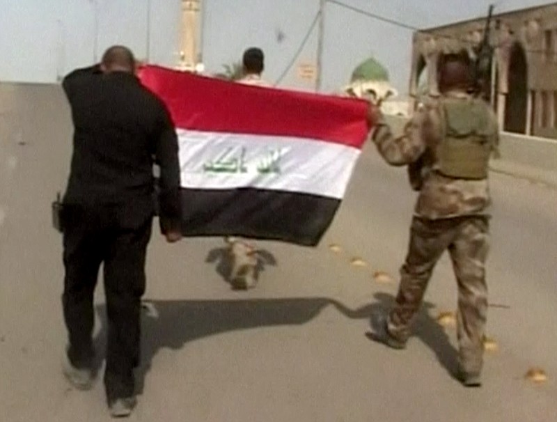
              This image made from Associated Press video shows, Iraqi soldiers carrying an Iraqi flag to hoist on buildings after a senior Iraqi commander declared that the city of Fallujah was "fully liberated" from Islamic State group militants, in Fallujah, Iraq, Sunday, June 26, 2016. (AP Video via AP)
            