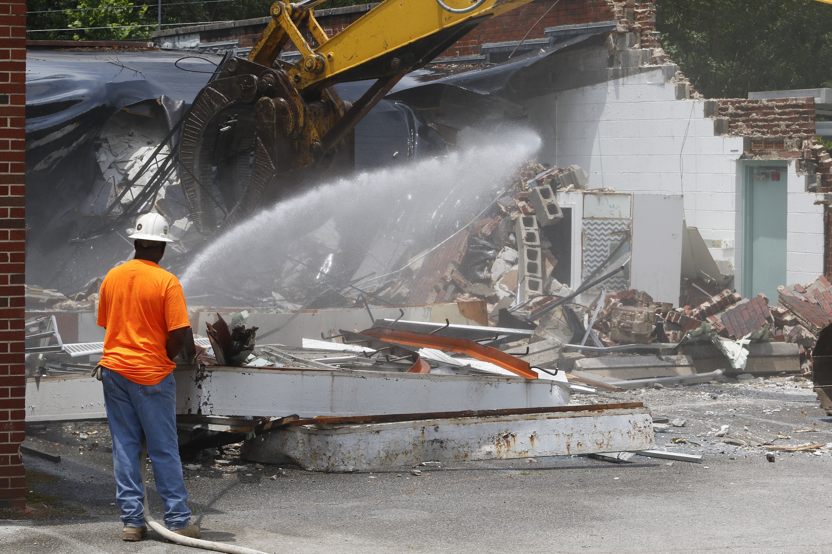 Scottie Williams, project superintendent with D.H.Griffin Wrecking Company, knocks down the dust as demolition begins.