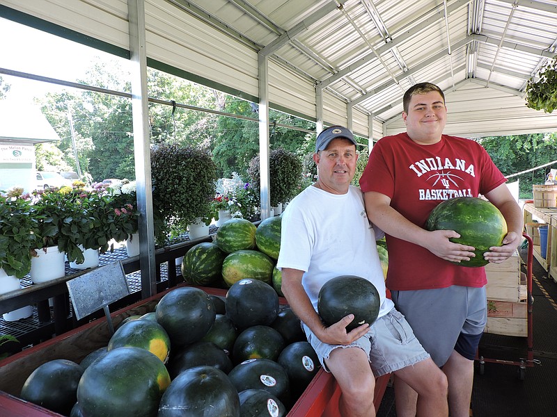 Melon Patch Farmer's Market owner Trey Deck, left, and his son Jacob Deck hold a sugar baby watermelon and a seedless watermelon, respectively.