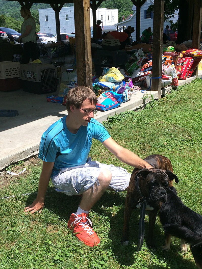 
              Flood survivor T.J. Parker plays with his dog, Titan, at the Ansted Baptist Church in Ansted, West Virginia, on Sunday, June 26, 2016. Parker says his home was already under water when he arrived from work Thursday. He says he and Titan then swam four blocks to safety. Along the way, he stopped to rescue an elderly man calling for help and brought him through floodwaters to a fire department. (AP Photo/Dave Morrison)
            